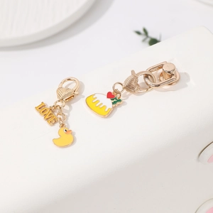 Detailed view of yellow enamel duck and LOVE charms with golden heart-shaped lobster clasps