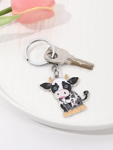 Close-up of a cartoon cow keychain with black and white enamel detail on a tray