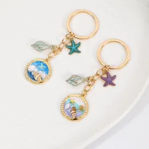 Joli porte-clés en métal avec pendentif de coquillage et étoile de mer sur plat en porcelaine