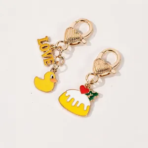 Golden keychain featuring a yellow cartoon duck and LOVE lettering charms on a white stand