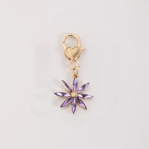 Porte-clés doré avec pendentif fleur à huit pétales en cristal violet sur fond blanc