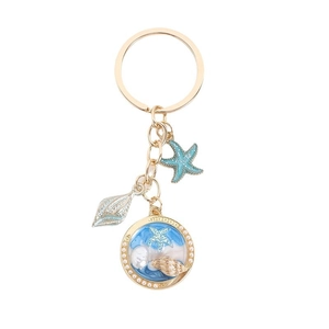 Porte-clés étoile de mer dorée et coquillage avec paillettes bleues sur fond blanc