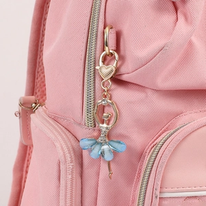 Porte-clés ballerine dorée avec cristaux bleus accroché à un sac à dos rose