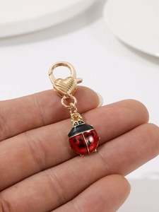 Vue détaillée d'un pendentif coccinelle 3D en émail rouge avec un fermoir mousqueton doré