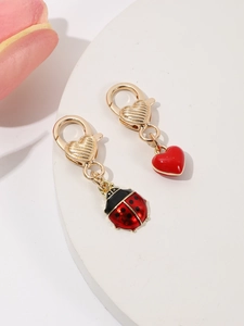 Détail de fermoirs mousquetons dorés en forme de cœur avec pendentifs cœur et coccinelle