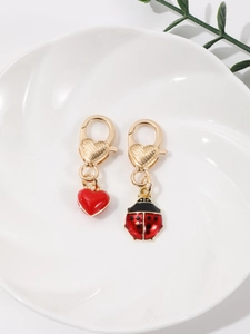 Détail des charms cœur rouge et coccinelle avec fermoirs mousquetons dorés texturés