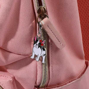 Detailaufnahme eines Emaille-Bulldoggen-Anhängers an einem rosa Rucksack-Reißverschluss