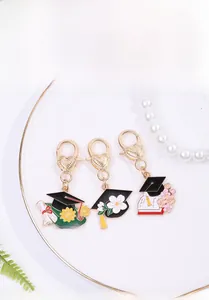 Detail of graduation cap charms with lobster clasp on a white decorative plate