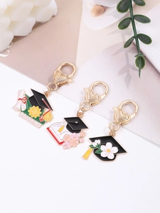 Close-up of three graduation charms with black mortarboard, scrolls, and golden heart clasps
