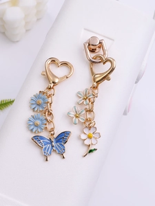 Detailed close-up of blue butterfly and white flower metal charms with heart clasp