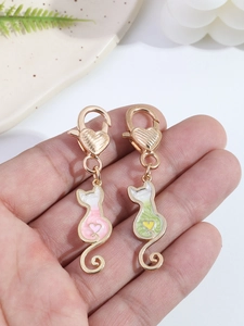 Detalle de colgantes de gato en esmalte rosa y verde con motivo de corazón y cierre dorado