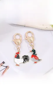 Detail of metal enamel rooster and duck keychains with heart-shaped spring clasps