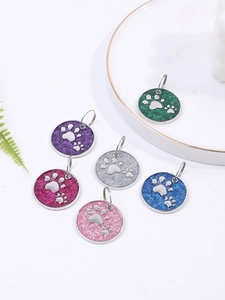 Detail showing six colorful glitter metal pet ID tags with paw prints in varied hues