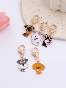 Detailed view of 5 cartoon dog charms with golden lobster clasps on a ceramic plate