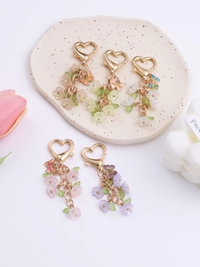 Detailed close-up of floral keychain charms with butterfly accents and gold heart clasps