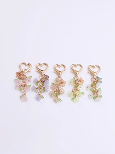 Detail of colorful floral bag charms with golden heart clasps in five pastel colors