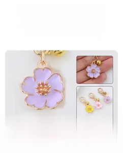 Detail of enameled cherry blossom charm with golden bell and lobster clasp connector