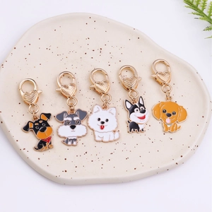 Set of 5 cute cartoon dog keychains with golden heart clasps on a ceramic tray