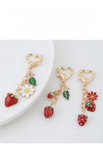 Detail of metal strawberry keychain with enamel daisy flower charms and heart lobster clasp