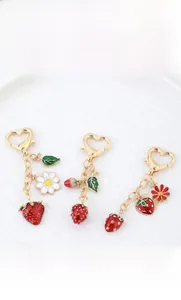 Macro shot of strawberry keychain with red enamel fruits and golden heart clasp on white tray