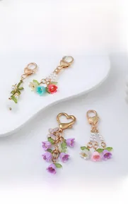 Close-up of colorful lily of the valley and tulip keychains with gold heart clasps