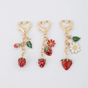 Three-piece strawberry charm keychain set with golden heart clasps and daisy details