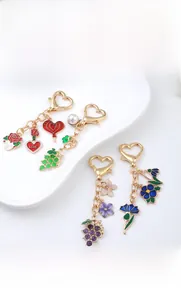 Détail de porte-clés floraux en émail avec mousqueton cœur doré et accents de perles