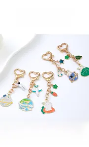 Flat lay of colorful enamel astronaut and planet keychains with golden heart clips