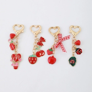 Porte-clés pastel avec breloques pomme et fraise et détails de nœud rouge