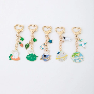 5-piece set of cartoon space rabbit keychains with gold heart clasps on white background