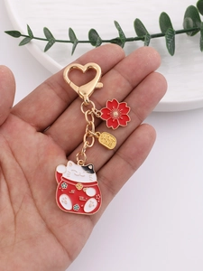 Detail of cute lucky cat keychain with red petals and golden lucky charm heart clasp