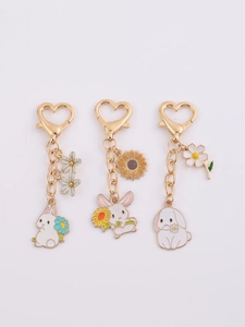 Detail of three cute enamel rabbit keychains with gold heart clasps and flower pendants