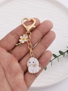 Detail of cute enamel rabbit keychain with golden heart clasp and small flower charm
