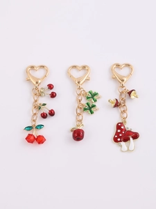Detail of alloy keychains featuring cherry, clover apple, and mushroom charms with heart clasp