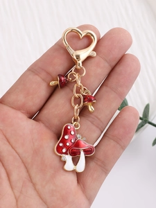 Detailed view of mushroom keychain with red enamel drip and golden heart-shaped clasp