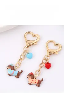 Détail de breloques teckel en émail avec fermoirs coeur dorés et petits pendentifs