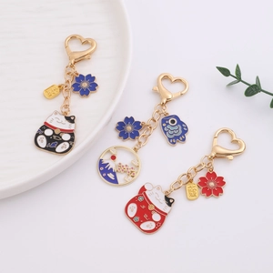 Japanese style lucky cat keychain set with gold metal pendants on white background