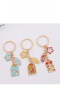 Detail of three metal keychains featuring cherry blossoms, koi fish, and lucky charms