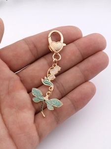 Detailed close-up of dragonfly keychain with green enamel flower and heart lobster clasp