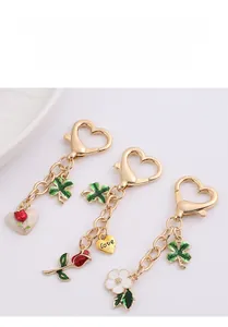 Detailed view of rose and clover enamel pendants with heart-shaped gold lobster clasps