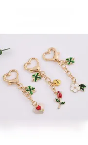 Detailed close-up of gold heart-shaped keychain with red rose and love engraving