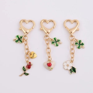 Three gold alloy heart keychains with rose and four-leaf clover charms in green enamel