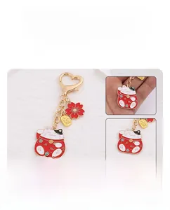 Detail of lucky cat keychain with red cherry blossom charm and heart-shaped metal clasp