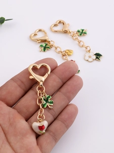 Detail of heart-shaped gold keychain with clover, flower, and Love engraving