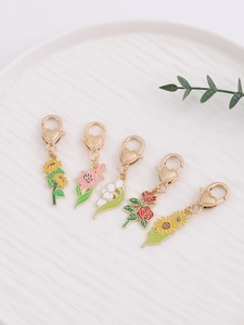 Détail de cinq breloques florales en émail avec fermoirs coeur dorés sur une assiette