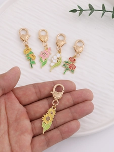 Détail des pendentifs floraux en alliage avec breloques de tournesol et rose en émail