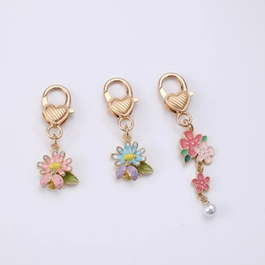Détail de breloques fleurs avec pétales en émail rose et bleu et un petit pendentif abeille