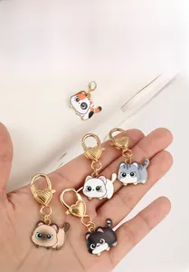 Five cute enamel cat keychains with gold heart-shaped clips held in hand