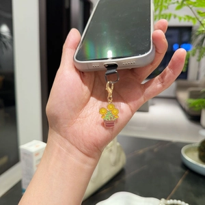 Bijou de téléphone tournesol avec fermoir doré et attache noire tenu dans la main