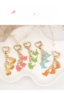 Close-up of five colorful cartoon dinosaur metal keychains with gold heart clasps